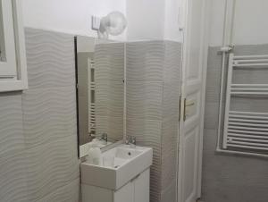 Baño blanco con lavabo y espejo en Sleepover City Center GuestRooms, en Budapest