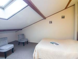 a attic bedroom with a bed and two chairs at Holiday Home Jardins de l'Océan-1 by Interhome in Saint-Georges-de-Didonne