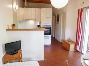 a kitchen with white cabinets and a flat screen tv at Holiday Home Les Palombes-3 by Interhome in Lacanau-Océan