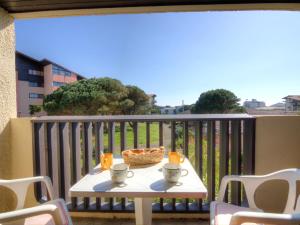 a table with two cups and a basket on a balcony at Apartment Douc-1 by Interhome in Seignosse