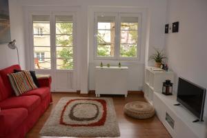 a living room with a red couch and two windows at Charming Apartment to feel Lisbon in Lisbon