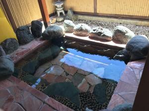 un étang dans un jardin avec des rochers et de l'eau dans l'établissement Fujibou Hotel, à Fujikawaguchiko