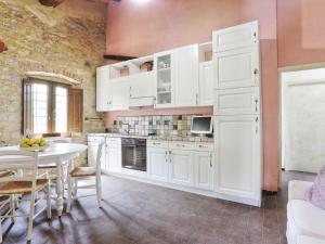 eine Küche mit weißen Schränken und einem Tisch in der Unterkunft Holiday Home Sweet Maremma by Interhome in SantʼAntonio