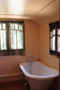 bañera blanca en una habitación con 2 ventanas en La roulotte "Les Saintes", en Saintes-Maries-de-la-Mer