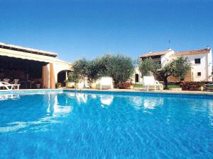 une grande piscine bleue avec des chaises et un bâtiment dans l'établissement Holiday Home Cucuron by Interhome, à Cucuron