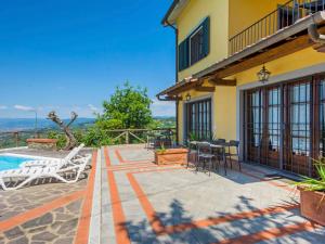 eine Terrasse mit einem Tisch und Stühlen neben einem Haus in der Unterkunft Apartment Poggio alla Baghera-1 by Interhome in Fornello