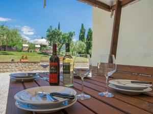 una mesa de madera con botellas de vino y copas. en Villa Beboli by Interhome, en Lamporecchio