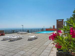a swimming pool with lounge chairs and the ocean at Apartment Il Cipresso by Interhome in San Baronto