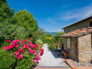 a garden with pink flowers and a stone building at Apartment Il Borghetto-3 by Interhome in Montecarelli