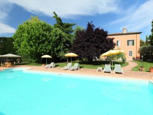 a large pool with chairs and umbrellas in front of a building at Villa Paolotti by Interhome in Bettona