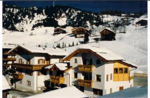 un grand bâtiment avec de la neige au sommet d'une montagne dans l'établissement Pensione Valbona, à Corvara in Badia