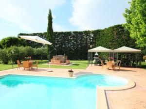 a swimming pool with tables and chairs and umbrellas at Villa Paolotti by Interhome in Bettona +35 photos