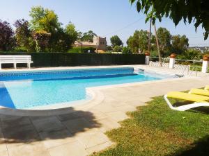 a swimming pool with two chairs and a bench at Holiday Home Eva by Interhome in Sant Antoni de Calonge