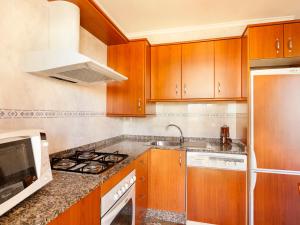 a kitchen with wooden cabinets and a stove top oven at Apartment Cascadas de la Marina-2 by Interhome in Denia
