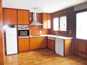 a kitchen with wooden cabinets and a white refrigerator at Holiday Home Eva by Interhome in Sant Antoni de Calonge