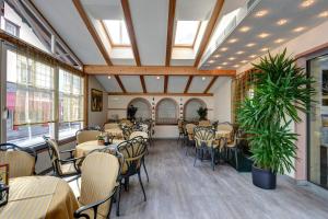 a dining room with tables and chairs and windows at Hotel Garni Schneider in Lutago
