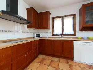 una cucina con armadi in legno, lavandino e finestra di Holiday Home Casa Ulldellops by Interhome a L'Ampolla
