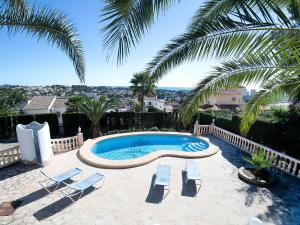 a swimming pool with two chairs and a palm tree at Holiday Home Casa Lina by Interhome in Calpe
