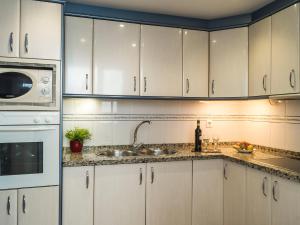 Apartment Las Terrazas by Interhome في مربلة: مطبخ بدولاب بيضاء ومغسلة وميكروويف