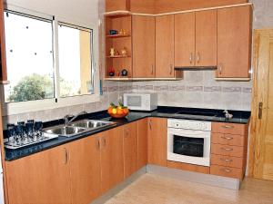 una cocina con armarios de madera y fregadero en Holiday Home Mestral by Interhome, en Alcanar