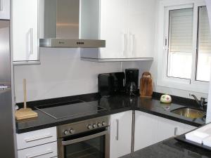 cocina con armarios blancos y encimera negra en Holiday Home Mimosa-3 by Interhome, en Denia