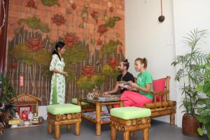 twee vrouwen en een man aan een tafel voor een muur bij Little Home Nha Trang Apartment in Nha Trang