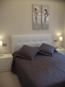 a bedroom with a bed with two pictures on the wall at Apartamentos Can Quim in L'Escala