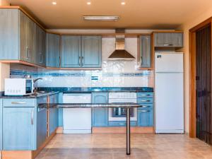 una cocina con armarios azules y electrodomésticos blancos en Apartment Golden Beach by Interhome, en Sant Carles de la Ràpita