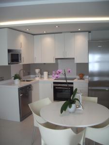 una cocina con armarios blancos y una mesa con flores. en Apartamentos Can Quim, en L'Escala