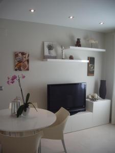 een woonkamer met een tafel en een televisie en een tafel en stoelen bij Apartamentos Can Quim in L'Escala