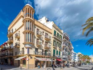 un edificio alto con una torre de reloj en una calle en Apartment Primer de Maig by Interhome, en Sitges