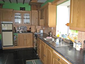 a kitchen with wooden cabinets and a sink and a refrigerator at Holiday Home Glenrath by Interhome in Dernagree