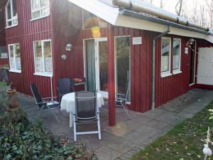 ein rotes Haus mit einem Tisch und Stühlen auf einer Terrasse in der Unterkunft Holiday Home Ferienpark Extertal by Interhome in Rott