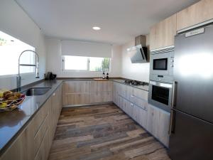 a kitchen with stainless steel appliances and wooden cabinets at Villa Trebol by Interhome in Calpe +27 photos