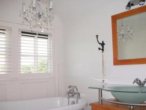 ein Badezimmer mit einem Kronleuchter, einer Badewanne und einem Waschbecken in der Unterkunft Holiday Home Wiringherlant-7 by Interhome in Noordstroe