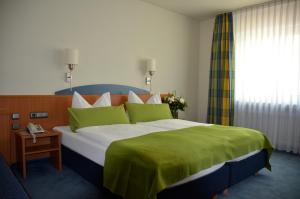 a bedroom with a large bed with a green blanket at Landhotel Sulzbacher Hof in Frankfurt/Main