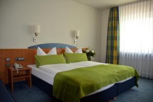 a bedroom with a large bed with a green blanket at Landhotel Sulzbacher Hof in Frankfurt