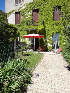 une terrasse avec un parasol rouge à côté d'un bâtiment dans l'établissement Appartements Maison Miro, à Carcassonne