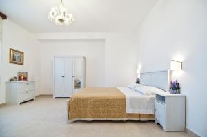 a white bedroom with a bed and a chandelier at Home Holiday Salento La Scisa in Alessano