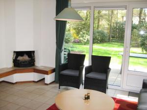 een woonkamer met 2 stoelen, een tafel en een open haard bij Holiday Home Bosrijk Ruighenrode-5 by Interhome in Lochem