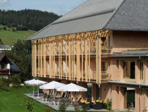 a building with tables and umbrellas in front of it at Natur & Wellnesshotel Breggers Schwanen - Bernau im Schwarzwald in Bernau im Schwarzwald