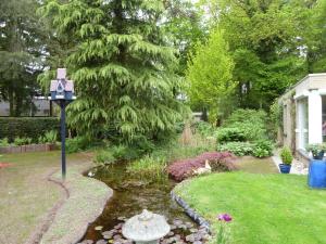 een tuin met een vijver en een vogelbad in de tuin bij Holiday Home Bosrijk Ruighenrode-3 by Interhome in Lochem