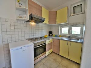 a small kitchen with yellow cabinets and a stove at Apartment Golub-4 by Interhome in Cesarica