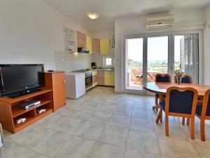 a kitchen and dining room with a table and a television at Apartment Golub-4 by Interhome in Cesarica