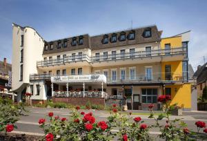 un grand bâtiment avec des fleurs rouges devant lui dans l'établissement Hotel Pohl, à Kinheim