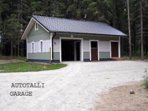 a building with a garage in the woods at Holiday Home Kärkelä by Interhome in Sulkava