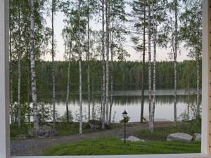 a view of a lake with trees and a lamp at Holiday Home Mielikki by Interhome in Kurkimaki