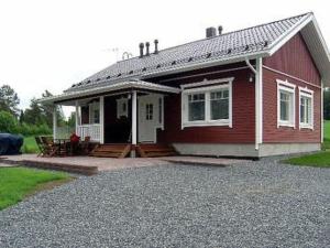 een rood huis met een veranda en een patio bij Holiday Home Talvikki by Interhome in Kurkimaki