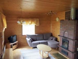 ein Wohnzimmer mit einem Sofa und einem Kamin in der Unterkunft Holiday Home Törmä by Interhome in Koivujärvi
