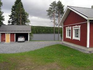 een rood huis met een auto in de garage bij Holiday Home Talvikki by Interhome in Kurkimaki